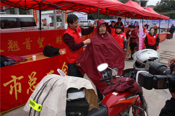梧州市總工會(huì)的黨員義工們?cè)谑袞|出口春運(yùn)服務(wù)站助力“摩托大軍”平安返鄉(xiāng)，幫助他們檢查車輛和行李，穿上雨衣。--黃賀峰攝.j